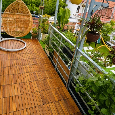Ban công lát vỉ gỗ với ghế treo và cây xanh